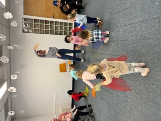 Young children in a group activity with fabric led by a teacher